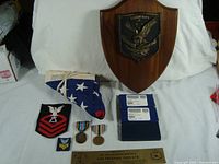 Collection of Navy memorabilia including the USS James K Polk plaque, folded US submarine flag, patches, medals, and nameplate.