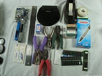 Full view of assortment showing stapler, ruler, staple remover, reusable clips, hole punches, slide rule, tape dispenser, and pen box