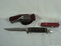 Three vintage blades shown laid out: Western hunting knife, Soviet multipurpose pocket tool with fork and spoon, Victorinox multipurpose tool.