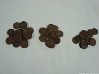 Three piles of loose circulated Lincoln Wheat pennies on a white surface showing overall quantity and condition.