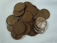 Loose stack and pile of Lincoln wheat pennies showing obverse side with Abraham Lincoln portrait and reverse side with wheat ears and denomination.