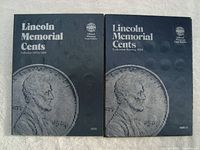 Two blue Whitman coin folders side by side with Lincoln's profile on the covers, labeled with collection dates 1959 to 1985 and starting 1959.