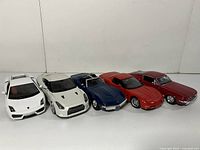 Front view of all five 1:24 scale model cars in white, silver, blue, and red arranged in a row.