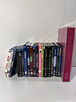 Photo showing 14 Blu-ray and DVD movie cases in a row with titles visible on the spines.