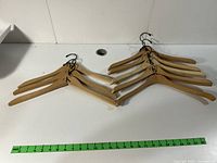 Top view showing all 8 natural wood Calvin Klein hangers fanned out with metal rotating hooks visible.