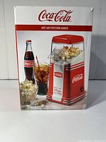 Photo of the original packaging box of the Coca-Cola hot air popcorn maker showing product image and branding.