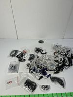 Overview of the lot showing tangled collection of earbuds in various colors including black, white, and blue, some packaged in plastic bags