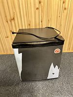 Front and side angle view of the mini refrigerator showing black exterior with visible wear.