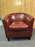 Front view of red leather armchair showing plush cushion and curved arms