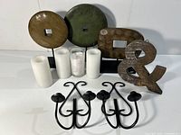 Overview of wooden decorative pieces on stands, wooden ampersand, black metal wall hooks, and white candles