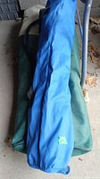 One photo shows two packed tents in blue and green fabric carry bags on floor.