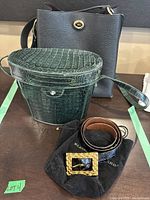 Three items displayed together: black Coach bucket bag, green croc purse, black belt on dustbag