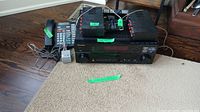 Photo showing Pioneer audio receiver, wired telephone, remote control, and two speakers arranged on floor and carpet.