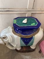 Full view of the elephant-shaped garden stool showing the blue and green glazed top and elephant body.