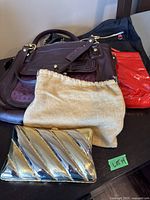 Shows three handbags in purple, red, and black colors, and one metallic silver clutch with diagonal stripes.