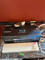 Sony Blu-ray Disc player box (BDP-S350) with power strip and tripod base visible beneath