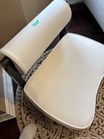 Side angled view of white leather seat and cylindrical backrest of black wooden meditation chair with short legs