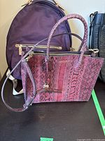 Pink Michael Kors purse featuring textured pink snake print leather, gold-tone logo, and zipper closure.