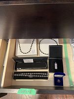 Silver necklaces, bracelet, pendant, pin, and ring arranged in drawer showing all items together