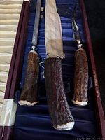 Close-up of three knives with stag horn handles in fabric-lined case