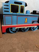 Left side of ride-on Thomas engine showing number 1 on wheel housing and painted details
