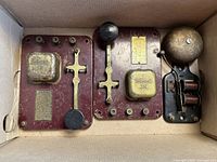 Top view of two antique telegraph devices and electric ringer bell placed inside a box showing the full lot