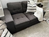 Front view of grey chenille loveseat with tufted seat and back, styled with pillows.