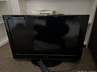 Front view of Dynex 32 inch LCD television showing the screen, black frame, and stand.