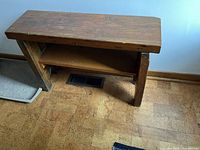 Front view of the sturdy wooden bench showing the shelf underneath and wood grain top surface.