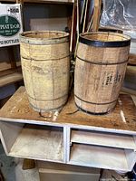Two vintage wooden nail kegs with metal bands on a wooden surface.