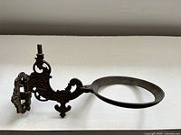 Side angled view showing overall shape, ornate scrollwork and circular opening for oil lamp.