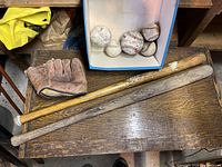 Top view showing the vintage baseball glove, two wooden bats and six baseballs in a box on a wooden surface.