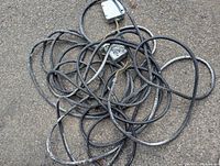 Tangled coil of black 10 gauge water resistant electrical wire with two attached gray metal junction boxes, showing signs of outdoor use and wear.