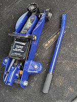 Full view photo of blue trolley car jack with detachable handle on black surface.