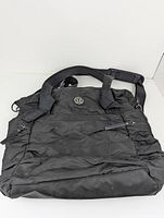 Front view of black Lululemon casual tote bag showing zipped pocket and logo