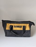 Front view of black and yellow canvas DeWalt drill bag with zipper and handles.