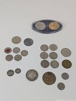 Top view of all coins laid out on white surface including commemorative coins in holder and assorted circulated coins