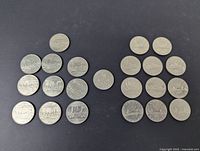 Photo of 22 Canadian one dollar coins, arranged in two groups on a black surface.