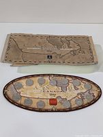 Display case with 13 Canadian Millennium quarters arranged in oval shape on Canada map background, original cardboard sleeve shown beside case.