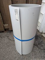 Rolled aluminum sheeting strapped with blue plastic band, standing upright on concrete surface