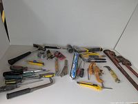 Full spread of all the assorted hand and construction tools laid out on white surface showing variety and condition
