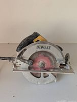 Side view of DeWalt circular saw showing blade, handle, and base plate with some dust and wear marks.