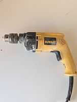 Side view of the yellow and black DeWalt hammer drill showing corded handle and metal chuck end