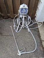 Front view of Graco Magnum TrueAirless X7 sprayer on wheeled stand with hoses and spray gun attached