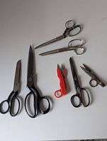 All seven scissors and snips of various sizes and colors, laid out on a white background showing different handle styles and blade lengths.