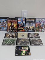 Photo showing all 12 game cases in a line including The Sims, Red Alert 3, Thomas the Tank Engine DVD game, Generals, and others.