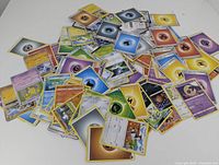 Photo showing a mixed pile of Pokemon cards including character cards and energy cards.