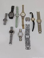 Photo of 11 assorted analog watches including metal, leather and fabric bands, with mixed sized round and square faces.