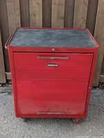 Front view of red Craftsman tool chest with two drawers and black rubber top mat, showing wear and dents.