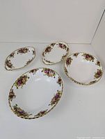Four pieces of Royal Albert Old Country Roses dinnerware (2 oval dishes and 2 serving bowls) arranged on white background.